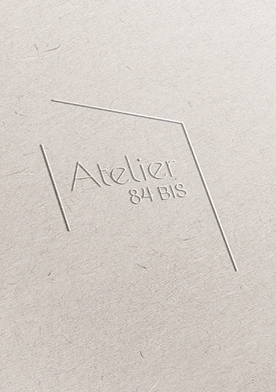 Logo de l’Atelier 84 bis imprimé en relief sur un papier gris texturé, déclinaison tactile de l’identité
