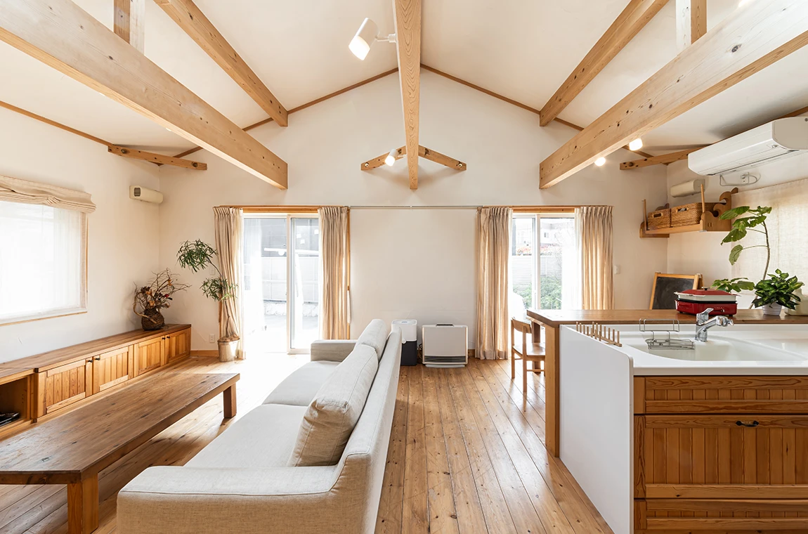 Séjour lumineux sous charpente en bois apparent, parquet et cuisine ouverte, ambiance menuiserie de l’Atelier Orma