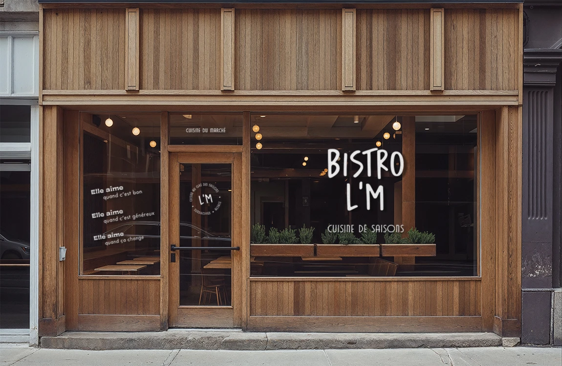 Devanture en bois du Bistro L’M avec enseigne en vitrophanie blanche et jeux de mots « Elle aime quand c’est bon »