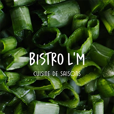 Logo Bistro L’M en blanc sur un gros plan de ciboulette ciselée, visuel de la direction artistique du restaurant