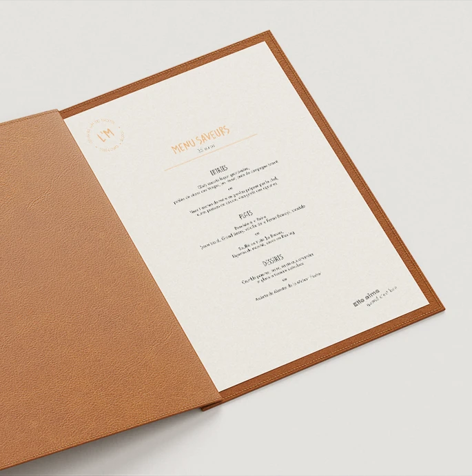 Menu Saveurs du Bistro L’M dans un protège-menu en cuir camel, entrées, plats et desserts en typographie orange et noire