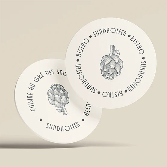 Sous-verres ronds du Bistro L’M illustrés d’un artichaut gravé, texte circulaire « Bistro Sundhoffen »
