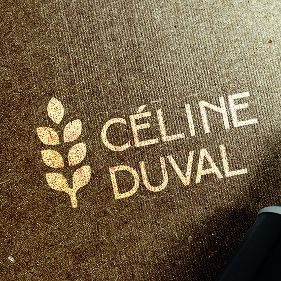 Logo de Céline Duval en ocre sur carton brun texturé, épi de blé stylisé et nom en capitales