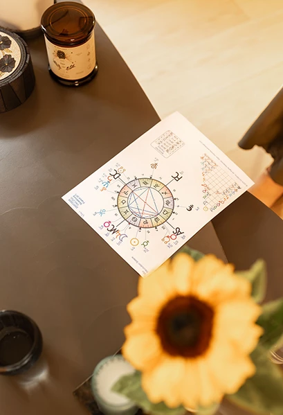Thème astral imprimé posé sur une table près d’un tournesol, scène de consultation de l’astrologue Céline Duval