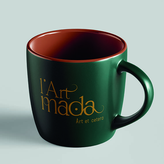 Mug vert sapin à l’intérieur terracotta, marqué du logo doré L’Art Mada et de sa baseline « Art et cetera »