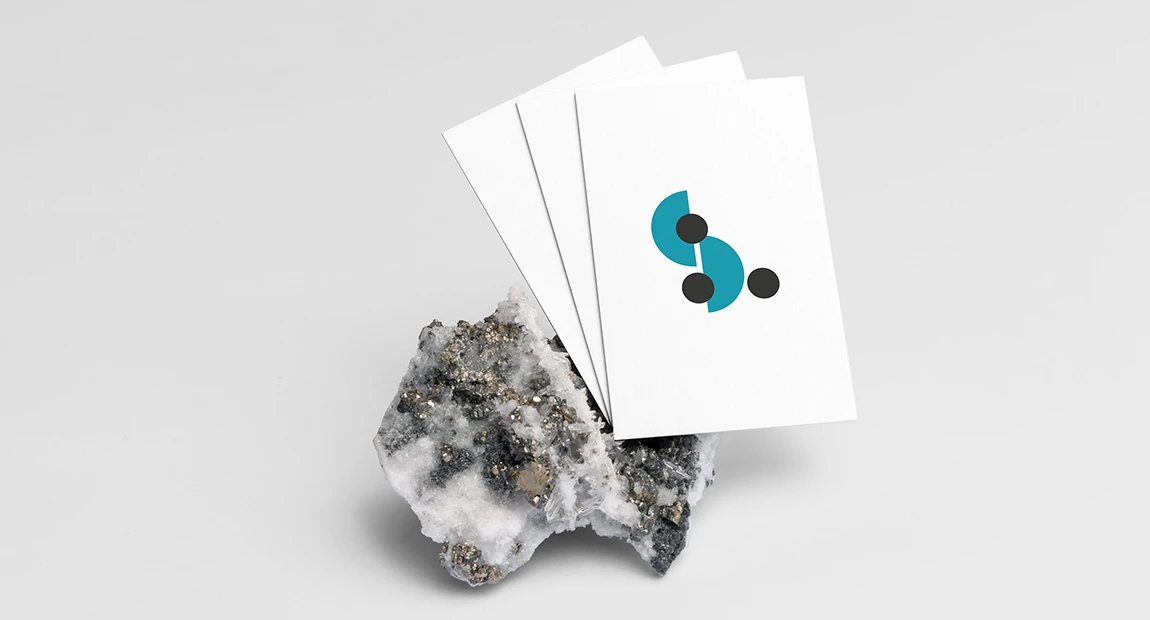 Cartes de visite blanches de La femme assise au logo turquoise et noir, posées contre une roche minérale