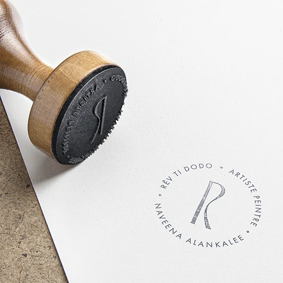 Tampon encreur en bois et monogramme R circulaire « Rêv ti dodo, artiste peintre, Naveena Alankalee » sur papier blanc